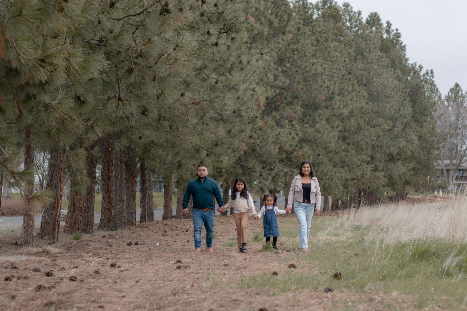 Family walking hand-in-hand through wooded trail during fall session in Pasco WA
