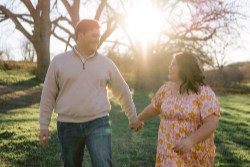 Couple holding hands and walking together in a sunlit park on a spring afternoon.