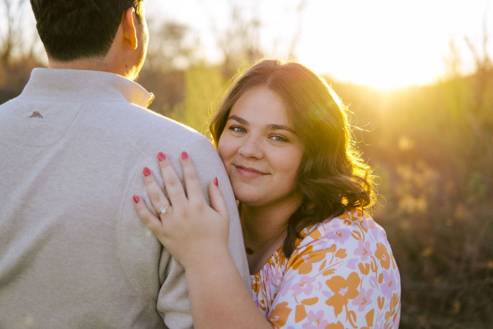 Couple embracing during golden hour sunset in a romantic outdoor setting.