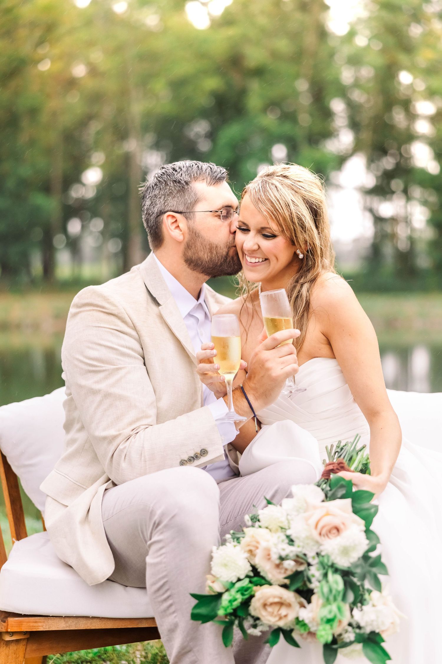 Elegant outdoor wedding celebration with champagne and floral arrangements by a lake.