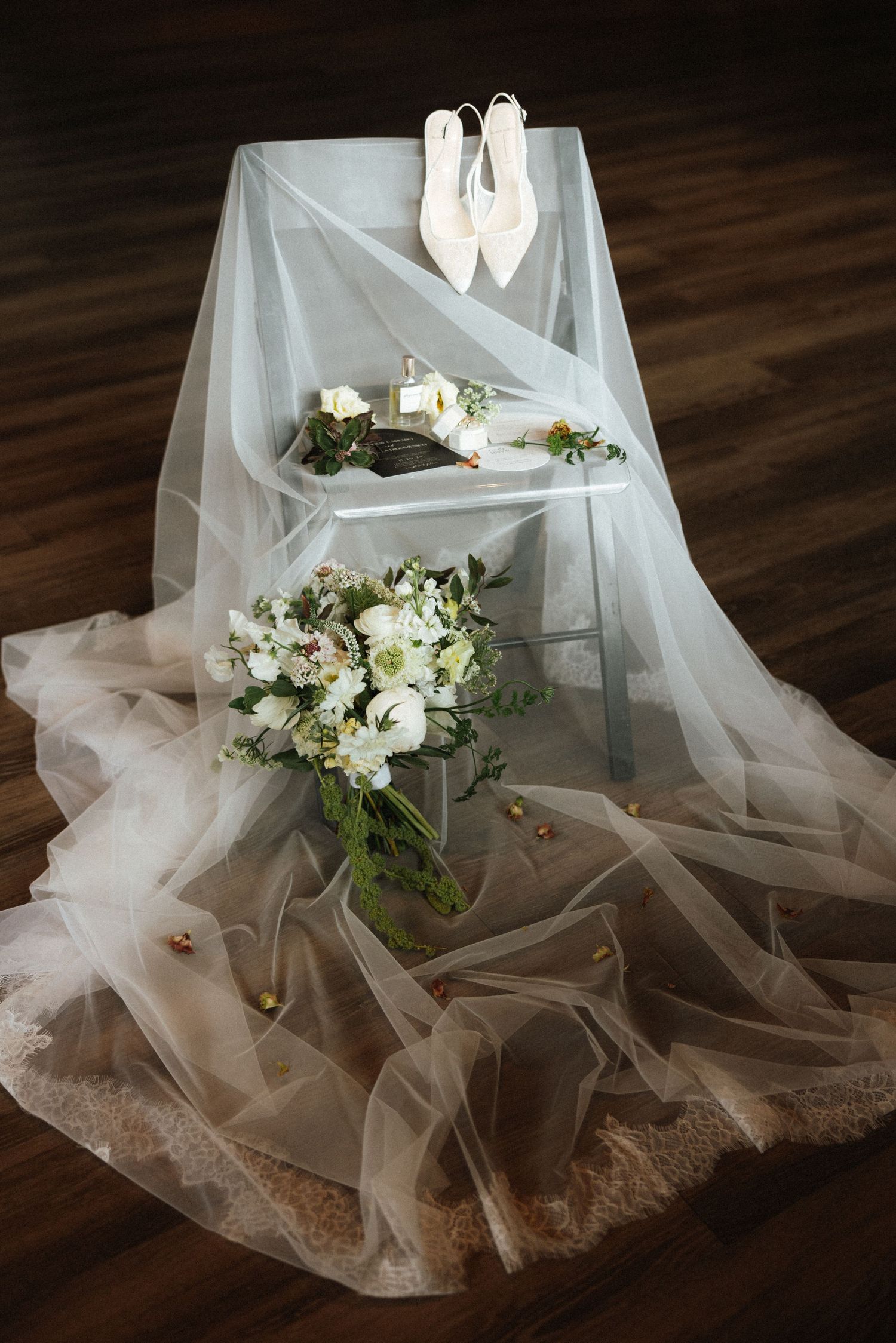 A pair of white ballet shoes hang on a lattice trellis against a dark background with green foliage. NJ wedding photographer