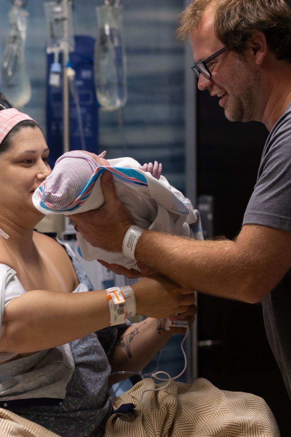 Two people tenderly care for a newborn baby in a hospital setting.