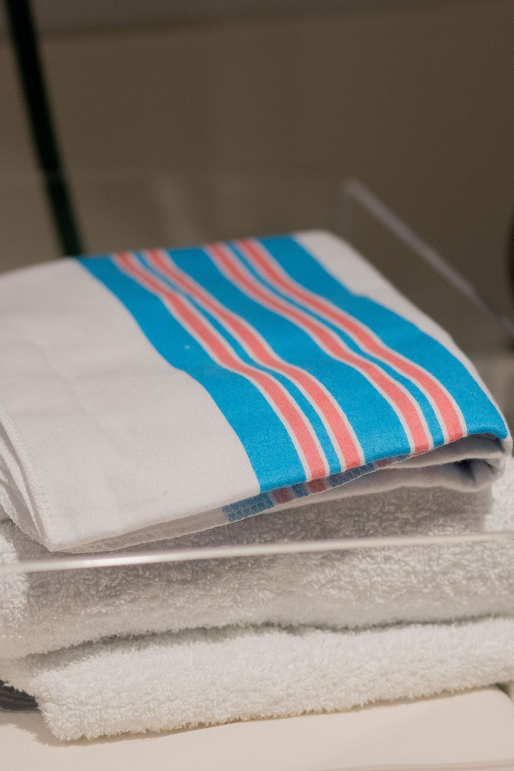 Close-up of a hospital towel with blue and pink stripes on a white surface.
