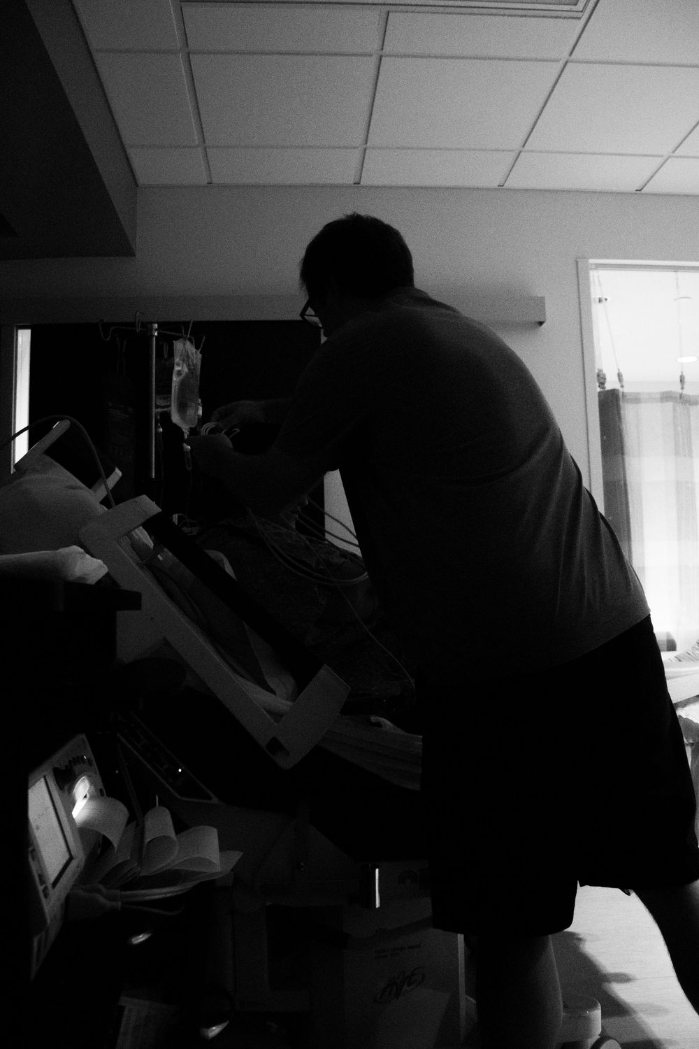 Silhouetted figures in a hospital room tend to a newborn.