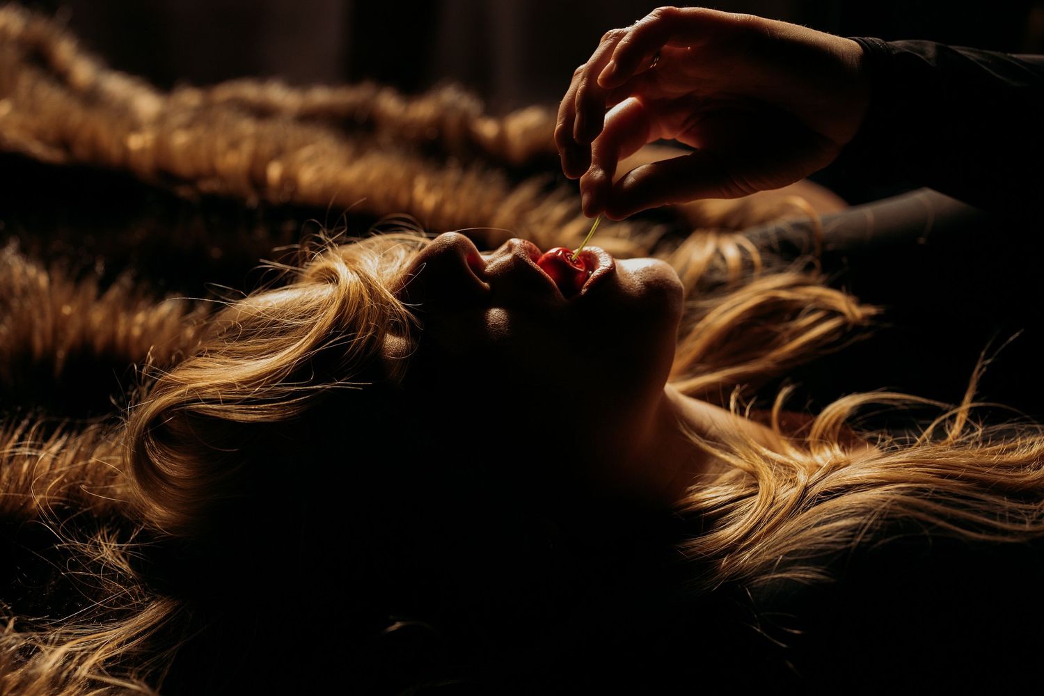 Artistic macro photograph of blonde hair strands illuminated by warm backlighting creating a glowing effect.