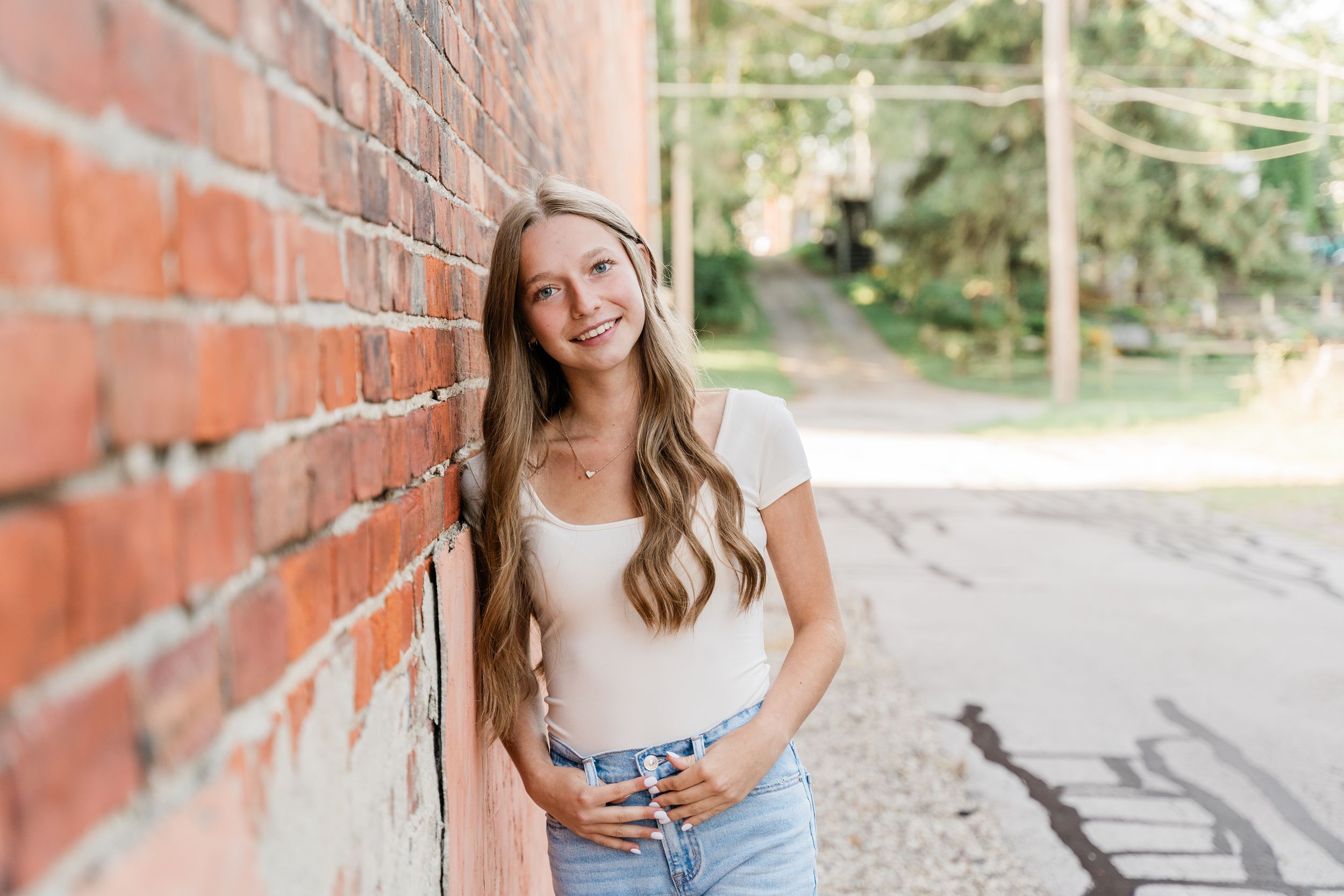 Students in casual attire posing near a brick wall during an outdoor photo session in a natural setting.