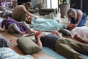 People relaxing on yoga mats during group meditation workshop.