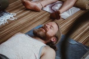 Person lying down on wooden floor during relaxation or therapy session.