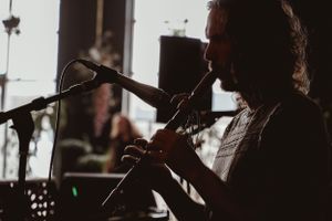 Silhouette of musician playing flute or wind instrument on stage with microphone.