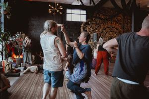 A group of people dancing and socializing in a dimly lit venue with decorative wall patterns.