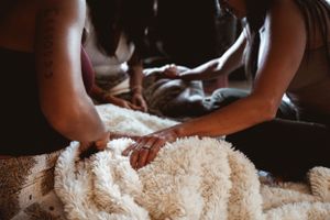 Hands knead into plush white fabric during a therapeutic treatment session.