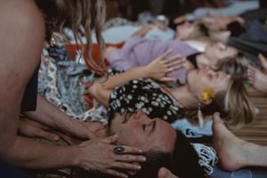 Hands providing therapeutic head massage during group wellness session.