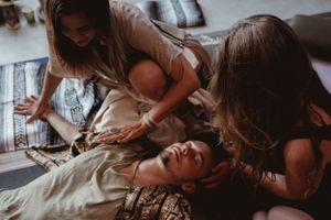 A therapeutic healing session takes place on cushions in natural lighting.