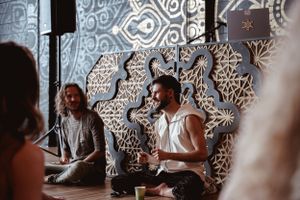 Wellness session leaders seated against intricate mandala wall pattern in modern studio.