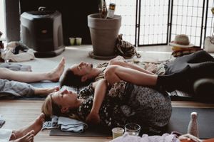 Group participating in restorative yoga or meditation practice on floor mats.
