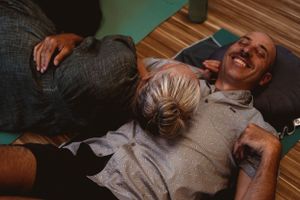 Two people share a joyful moment during a wellness session on the floor.