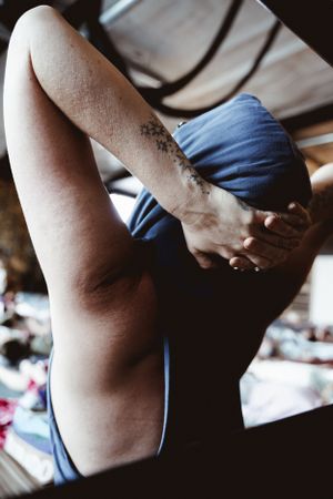 Person in blue activewear stretching with a small tattoo visible on their arm.