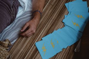 Hand resting near blue cards on wooden surface during wellness session.