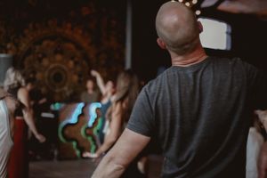 People dancing in a dark venue with ornate mandala patterns decorating the walls.