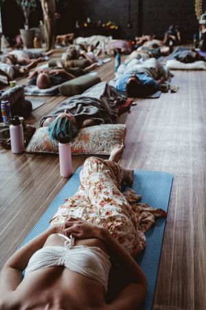 People lying on yoga mats during relaxation session in modern studio space.