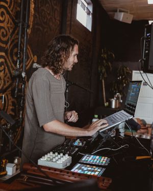 Music producer working with electronic equipment at performance setup.