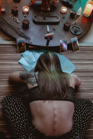 Overhead view of tarot cards and mystical objects arranged on wooden table.