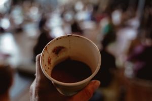 Close-up shot of a ceramic cup containing dark liquid against blurred background.