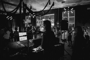 Silhouette of performer at mixing desk during nighttime event.