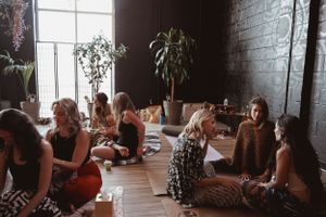 A wellness class gathers in a modern studio space with brick walls and plants.