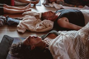 People lying on floor mats during group meditation or relaxation session.