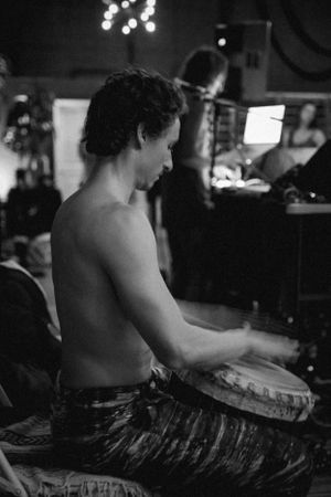 Musician plays percussion instrument in black and white atmospheric lighting.