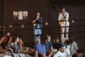 Group gathering in dimly lit room with candles and meditation setup.