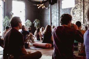 Participants sitting in meditation during wellness gathering with decorative wall art.