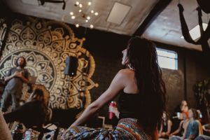 People participate in a movement class in front of a decorative mandala wall design.