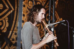 Musician playing trumpet against ornate mandala backdrop during meditation session.