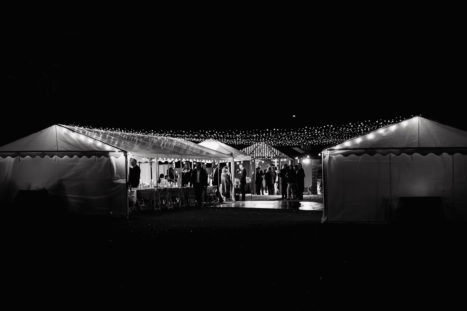 A couple shares their first dance at a wedding reception, with the bride wearing a sleek white gown.