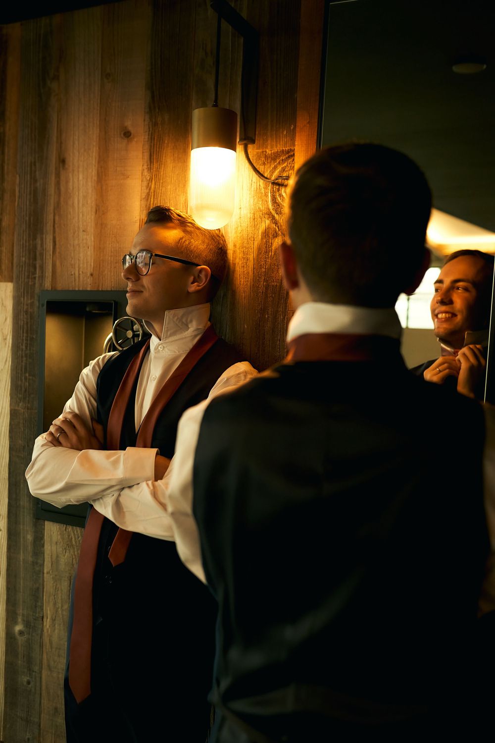 Couple in formal wear shares intimate moment in hallway with warm lighting.