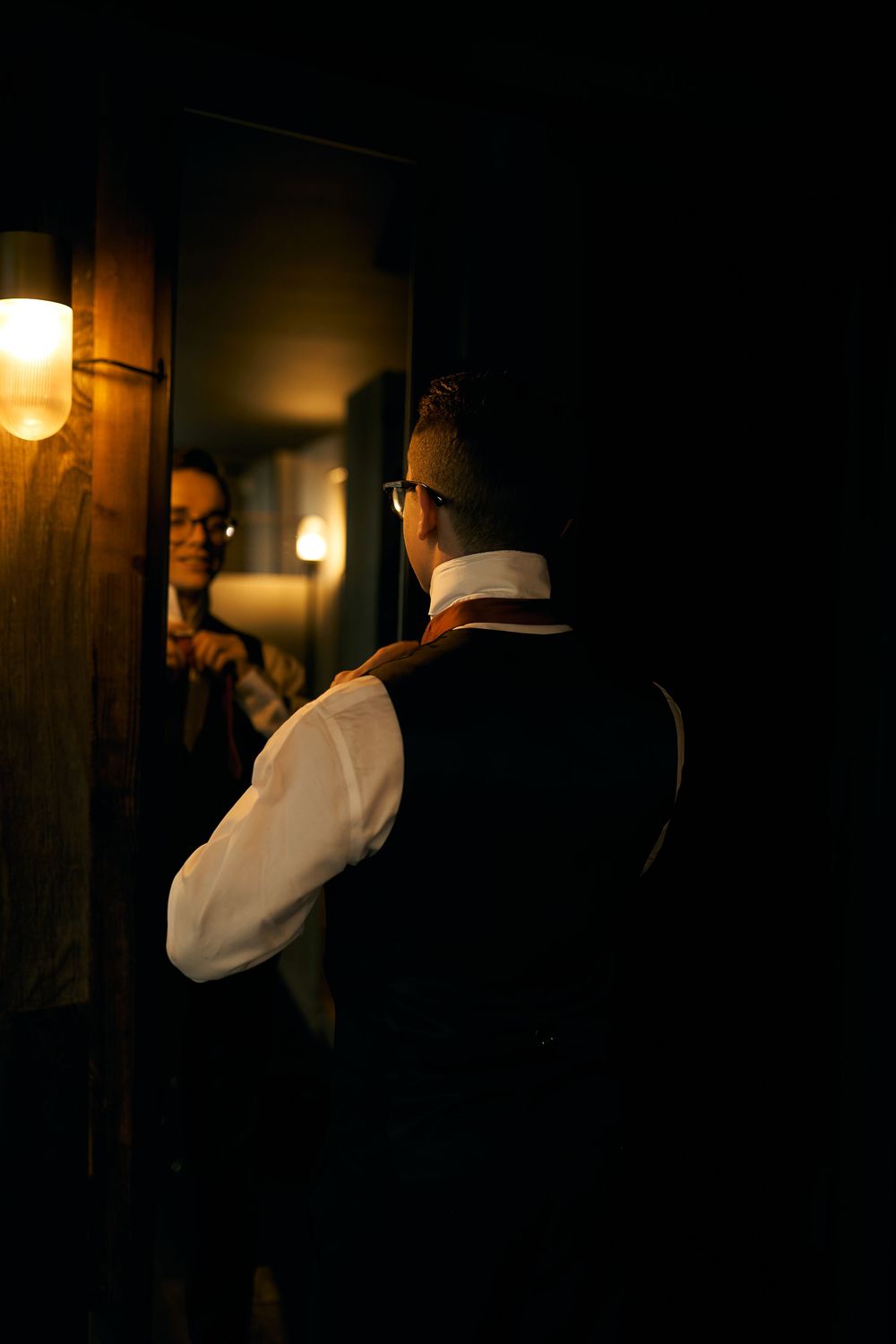 A silhouetted couple embraces in a dimly lit hallway with warm lighting.