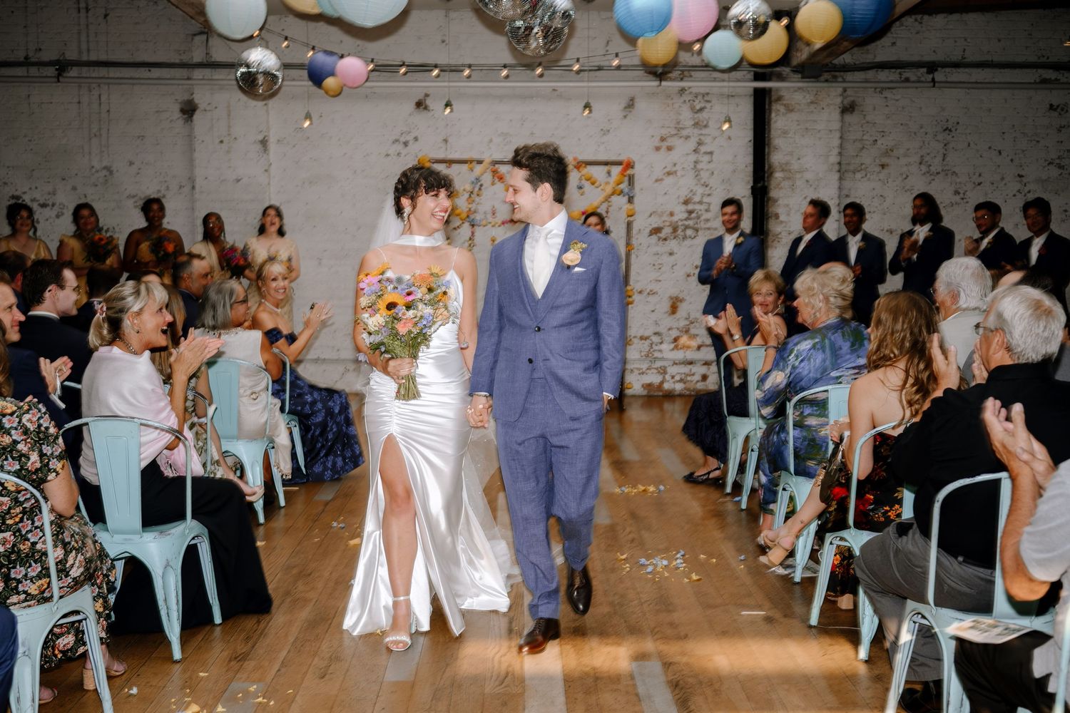 A beautiful rustic wedding reception features a white barn setting with turquoise chairs and festive balloon decorations.