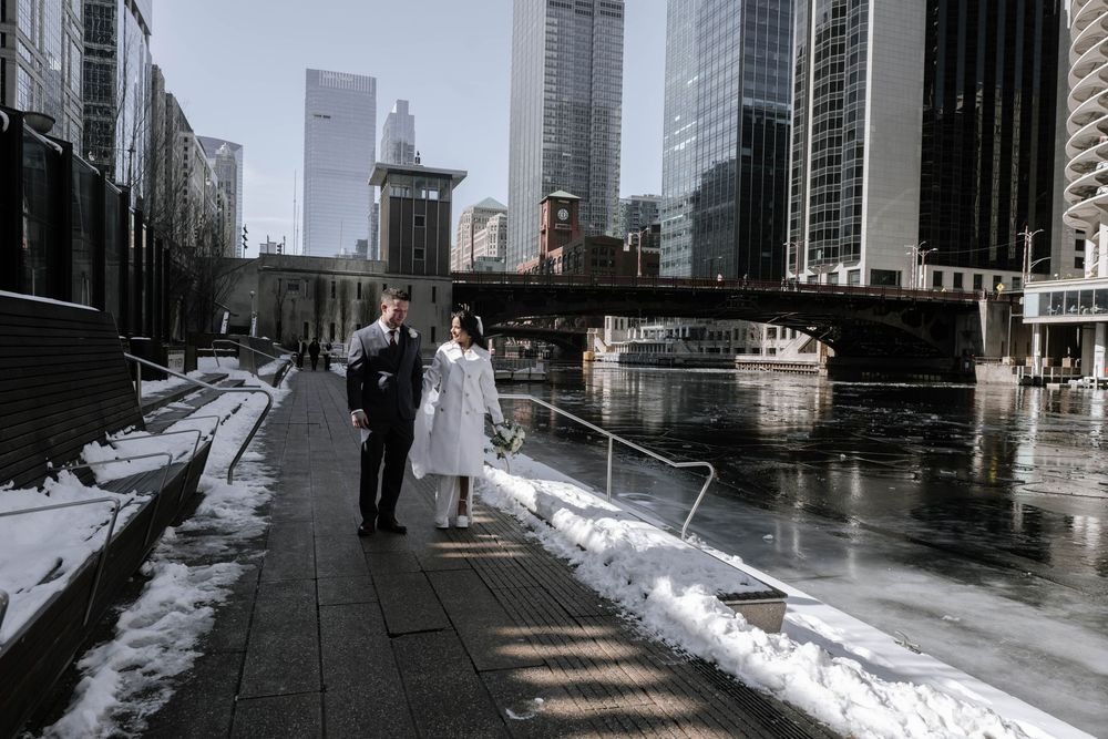 Snow covered sidewalks line a modern urban street with tall glass buildings and winter shadows.