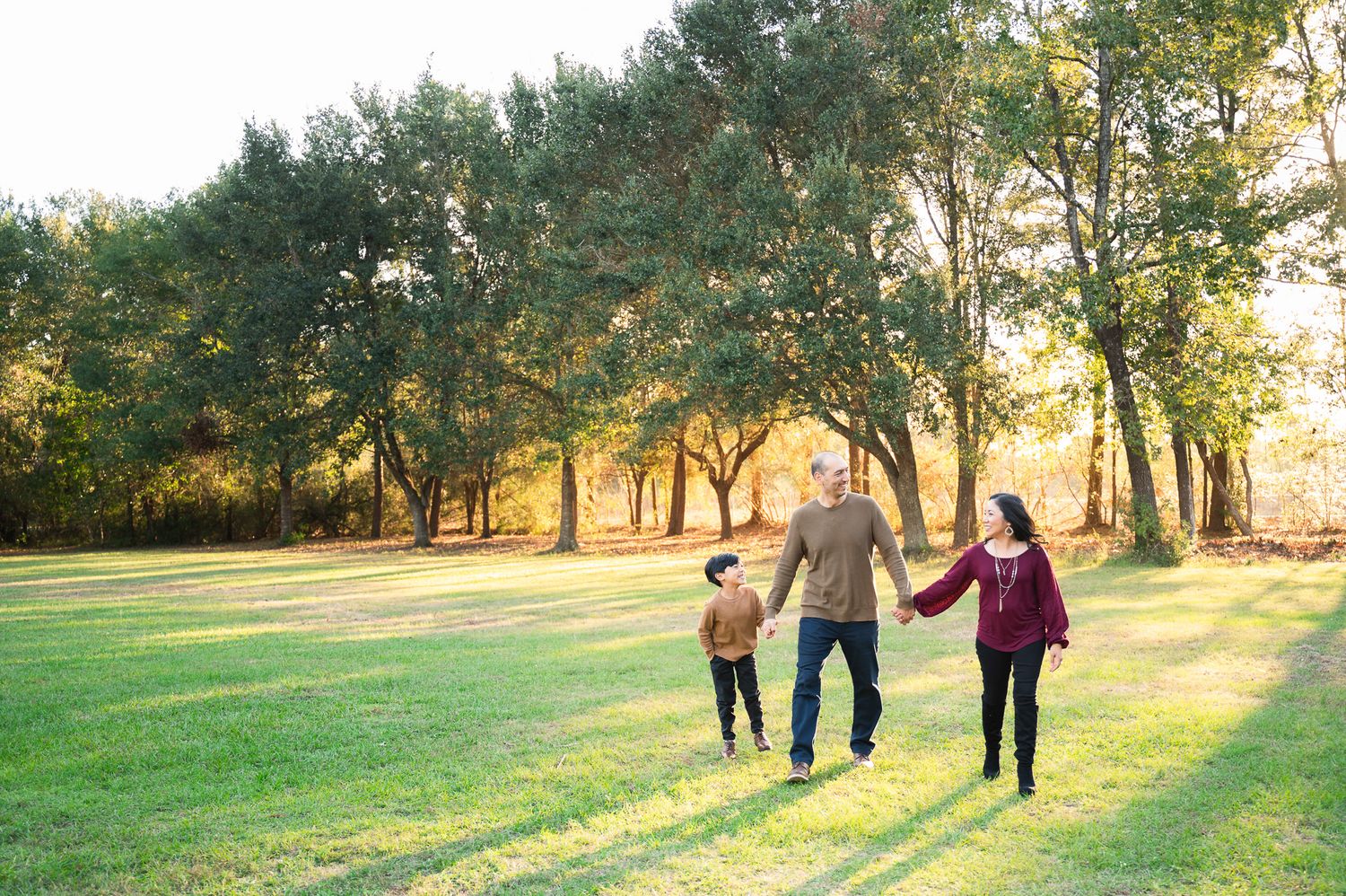 Family playing together with a soccer ball in a sunlit park during golden hour on a beautiful autumn day.