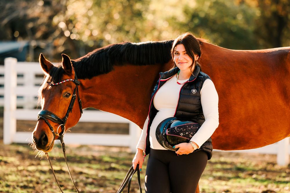 A peaceful autumn scene with a majestic bay horse and equestrian enjoying a moment together by a white fence.