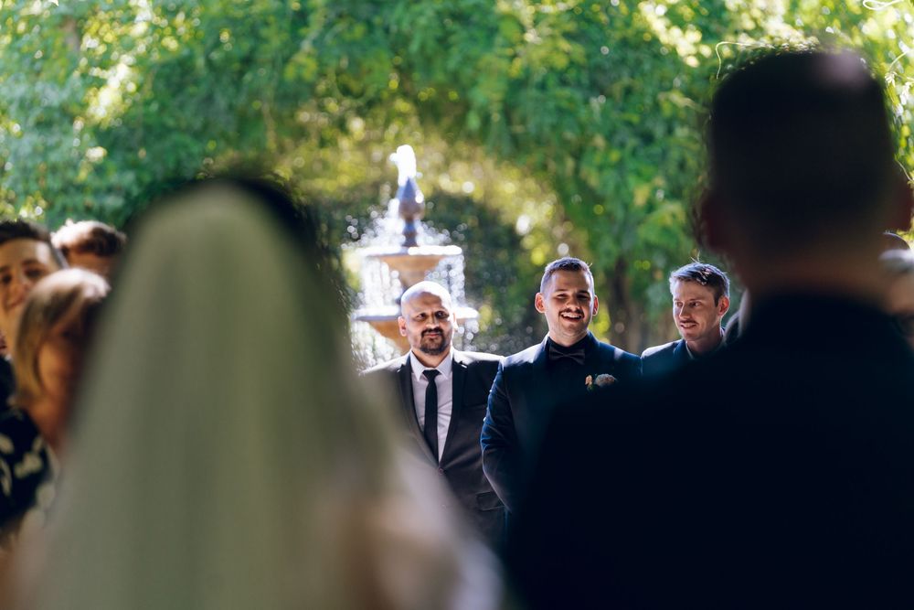 Wedding ceremony taking place in lush outdoor garden setting.