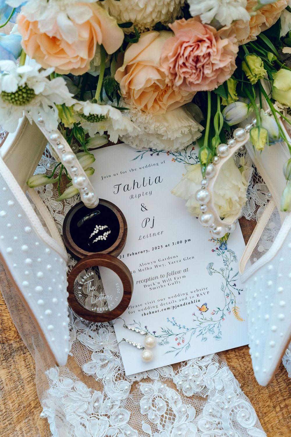 Wedding invitation with floral details surrounded by peach roses and white lace.