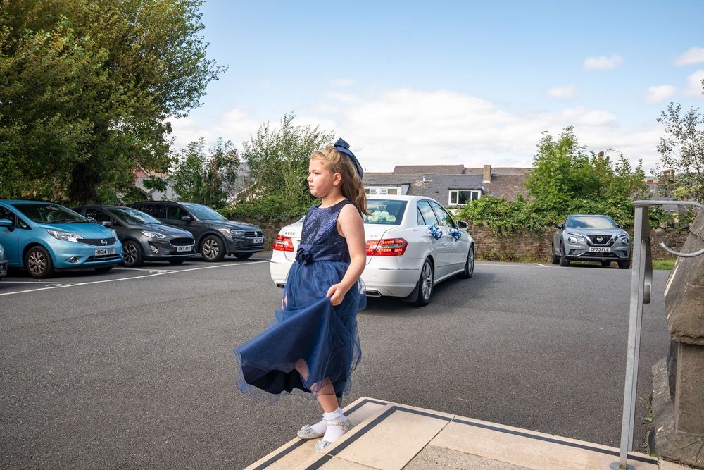 A person in a blue dress walks through a parking lot on a sunny day, captured in multiple sequential frames.