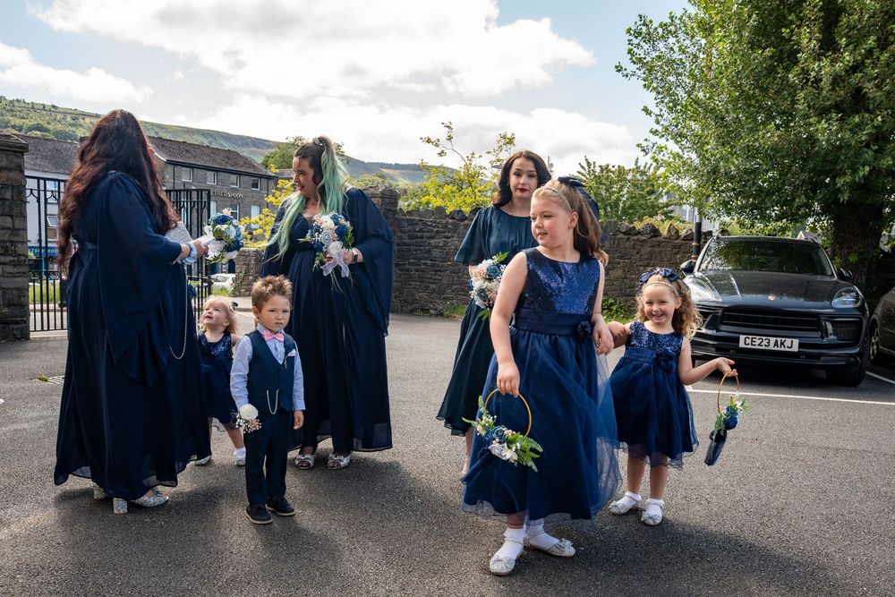 A group in coordinating navy blue and black formal attire gather together outdoors on a sunny day.