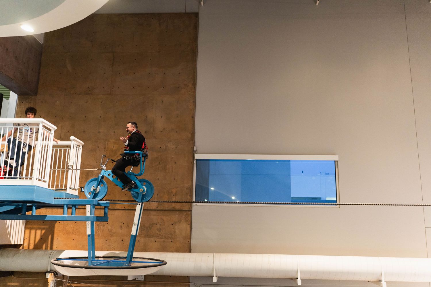 A person rides a blue bicycle on an elevated platform inside a modern museum exhibit.cinematic wedding photographer new mexico