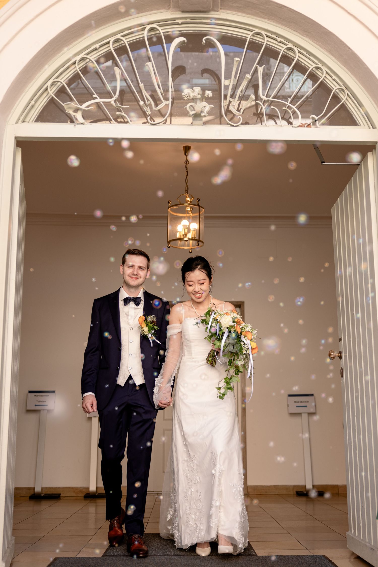 Confetti falls around newlyweds under arched doorway entrance.