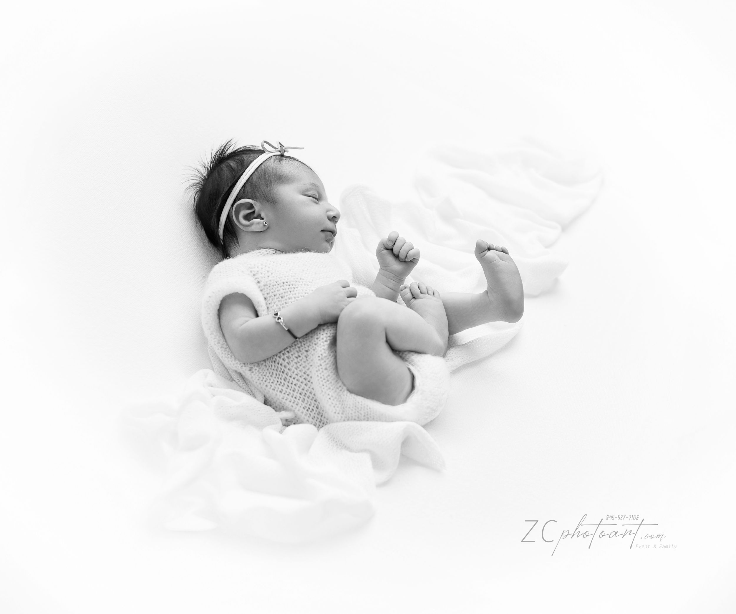 A black and white series of artistic photography showing a newborn baby in various resting positions on white fabric.