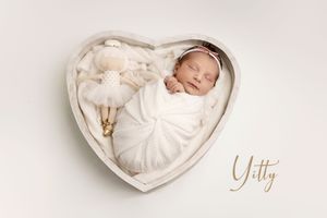 A series of four heartwarming newborn baby photos in white heart-shaped props against a soft neutral background.
